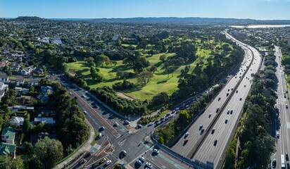 Aerial view of traffic on a highway and city streets in Western Springs, Auckland, New Zealand. Cars are driving, showcasing urban transportation and infrastructure.