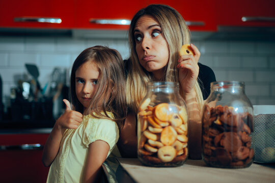 Little Girl Showing Thumbs up Enjoying Dessert with her Mom. Funny family having a snack together in the kitchen