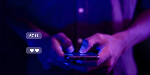 Close up of hands holding smartphone with social media notifications glowing in blue light