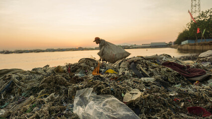 scavengers walking on piles of rubbish washed up on the shore near a fishing village in Indonesia...