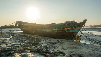 an old boat on the shore of the receding sea belonging to a traditional Indonesian sailor who used it to fish in shallow seas capture from side.