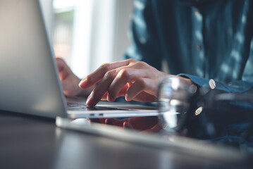 Close up, business woman hand typing, working on laptop computer on table office with sunlight. Woman online working, blogging with laptop, surfing the internet, social networking, internet technology