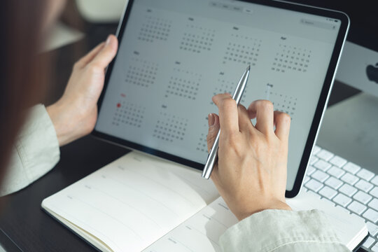 2026 Calendar event planner timetable agenda plan on organize schedule. Business woman using digital tablet with monthly calendar for event planning, Plan scheduling, writing on notebook at office