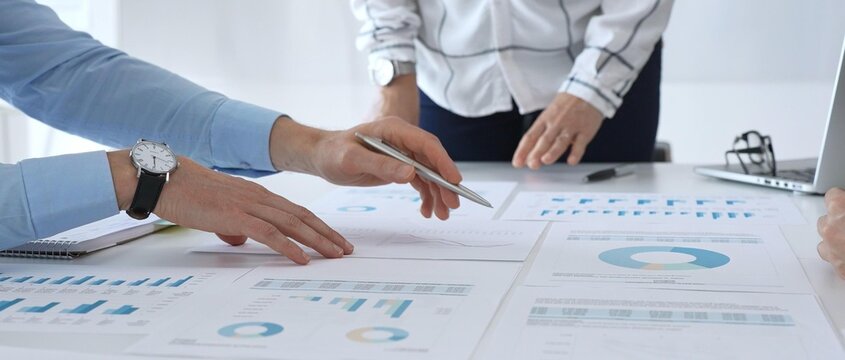 Business team discussing financial charts and strategy with graphs and data analysis documents on office desk during meeting for planning and corporate decisions