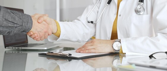 Doctor shaking hands with a patient, demonstrating agreement, trust, and successful consultation in...