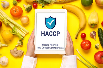 Woman holding tablet computer with text WORLD VEGAN DAY, vegetables and fruits on yellow background