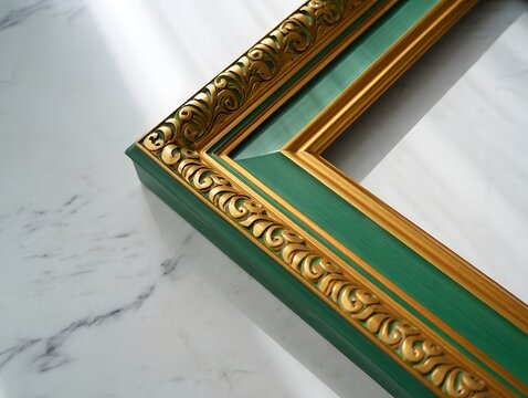 A green and gold frame corner with ornate detailing on a marble surface in soft light