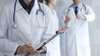 Medical professional writing on clipboard with stethoscope, a doctor and female assistant collaborating in a clinic, discussing patient data and healthcare information