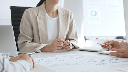 Business team analyzing financial data and discussing marketing strategy during a meeting in the office, businesswoman pointing at charts and explaining strategy to colleagues