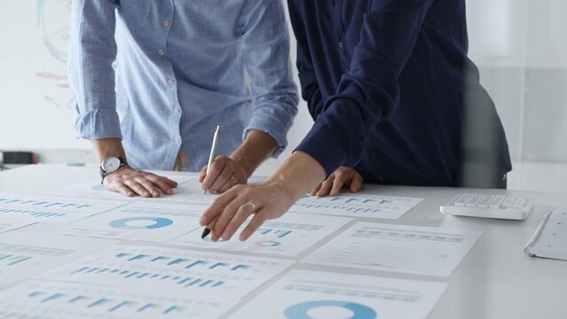 Professional business team analyzing financial reports, sharing insights and planning strategic decisions in modern workplace setting