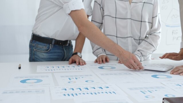 Professional team reviewing financial charts and graphs, working together in modern office environment, discussing strategic improvements. Business people concept