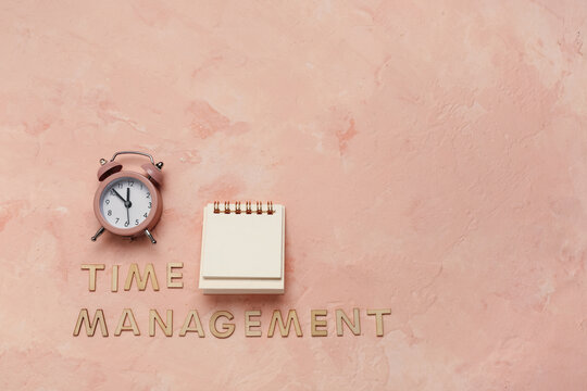 Text TIME MANAGEMENT, alarm clock and notebook on beige background. Top view