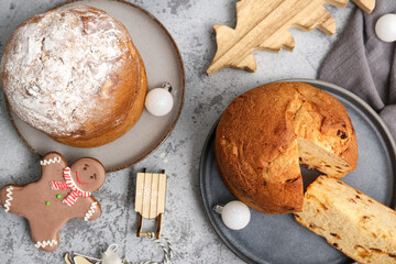 Plates with tasty Panettones, napkin and Christmas decor on grey grunge background