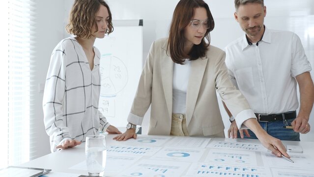 Professional team reviewing financial data, collaborating on working documents, demonstrating team achievements and positive dynamics in the workplace. Business people concept