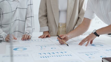 Business team working on financial charts and graphs, pointing at statistics and discussing business project data in modern office. Business people concept