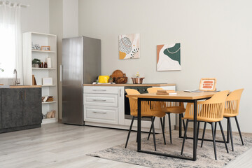 Dining table in interior of kitchen with fridge and counter
