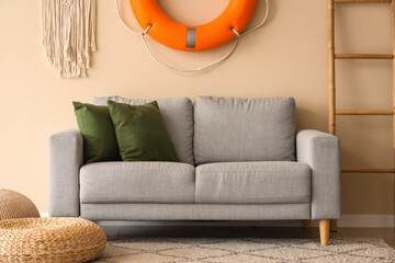 Cozy sofa, ladder, lifebuoy ring and poufs in living room