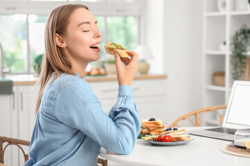 Beautiful young happy woman holding tasty toasts with fresh butter, avocado and blueberries in...