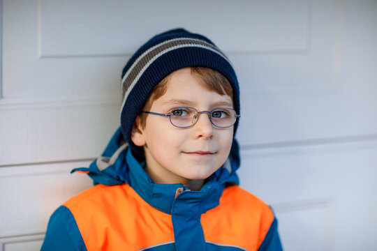 Portrait of little cute school kid boy with glasses and colorful winter fashion clothes. Child smiling and having fun with the camera. Winter, spring or autumn fashion. Kid with missing front teeth