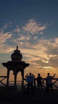 Young man enjoying the sunset and evening view at Samai Mata Mandir, Banswara, near Udaipur, Rajasthan, India, raising his hand in satisfaction while admiring the beautiful landscape.