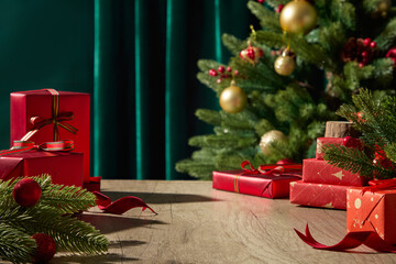 Red and gold Christmas gift boxes under soft warm light, pine tree with green curtain backdrop,...
