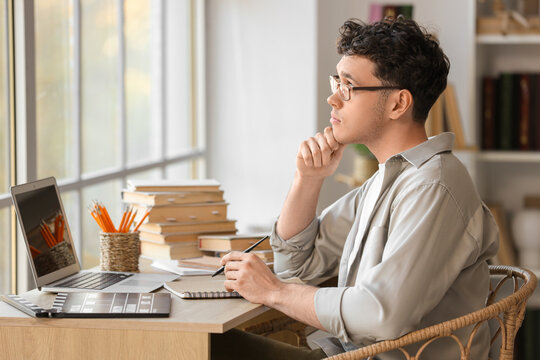 Thoughtful male screenwriter writing script at table in office