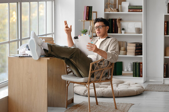 Male screenwriter reading script at table in office