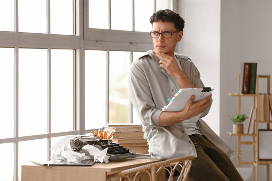 Thoughtful male screenwriter with script in office