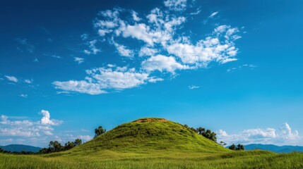 Lush Green Hill Under Blue Sky with Fluffy White Clouds in Vibrant Landscape Scene of Nature and Serenity in a Tranquil Environment
