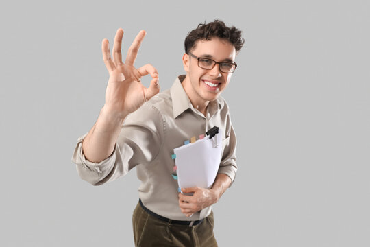 Young man with scenario showing OK on grey background