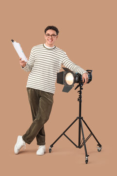 Male screenwriter with scenario and glowing lamp on beige background