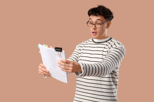 Shocked male screenwriter with scenario on beige background