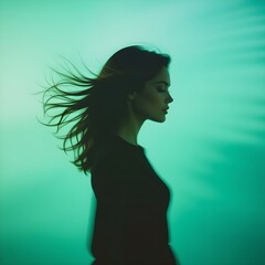 Side Profile Silhouette of Woman with Flowing Hair Against Teal Green Background
