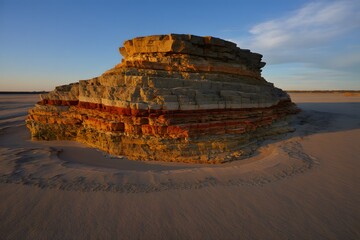 Layered rock formation in desert landscape under a clear blue sky at golden hour light