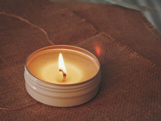 Scented candles glowing on a burlap sack at night, creating a romantic and warm atmosphere. Perfect for concepts of relaxation