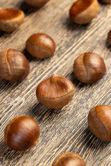 a hard edible chestnut fruit in a brown shell on a wooden table, a group of raw chestnut with a hard shell of brown color