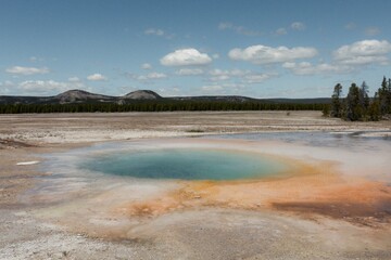 Blue geothermal pool surrounded by mineral-rich ground.