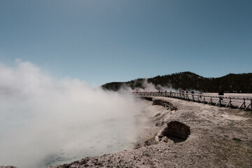 Steam rising along a boardwalk beside a geothermal pool.