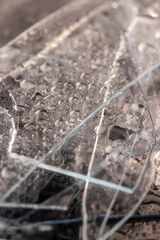broken wet old glass lies on a black slate board with an uneven texture, pieces of broken transparent glass covered with water close up