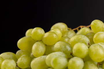 a branch of ripe beautiful green grapes lying on the table, covered with drops of water, wet fruits of pure grapes on a branch on the table during cooking