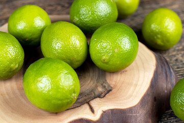 green ripe citrus limes scattered on a wooden table in the kitchen, ripe and juicy lime fruits for cooking both sauces and drinks and other food