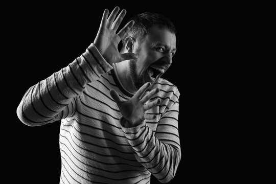 Scared young man screaming on black background