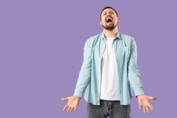 Screaming young man on lilac background