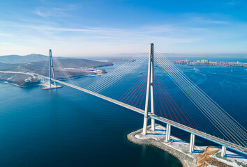 Obraz premium Stunning view of the Russky Bridge in Vladivostok with clear blue skies and tranquil waters.