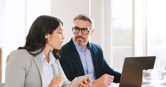 Review, advice or businesspeople in office with laptop, discussion or evaluation of sales proposal. Tech, assistance or manager in real estate agency with tablet, partnership or guidance for report.