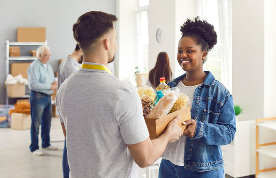 Volunteering people, food bank box giving help to african american woman, male volunteer working in charitable meal foundation making donation, charity separating basic need provisions, free meal help
