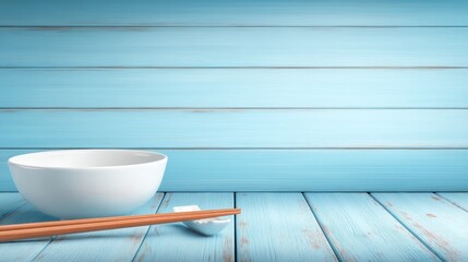 White bowl and pair of chopsticks resting on chopstick rest sit on light blue wooden table against matching wooden background