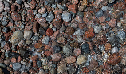 multicolored pebbles stones underwater sparkling in sunlight near the shore in sea background
