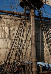 Fototapeta premium Detailed view of a tall ships mast and rigging under a blue sky.