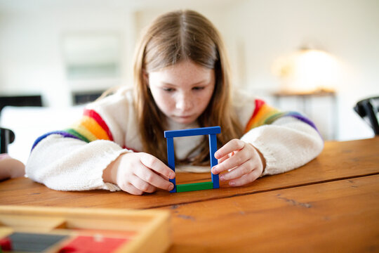 Young girl building colourful rectangular blocks on the table